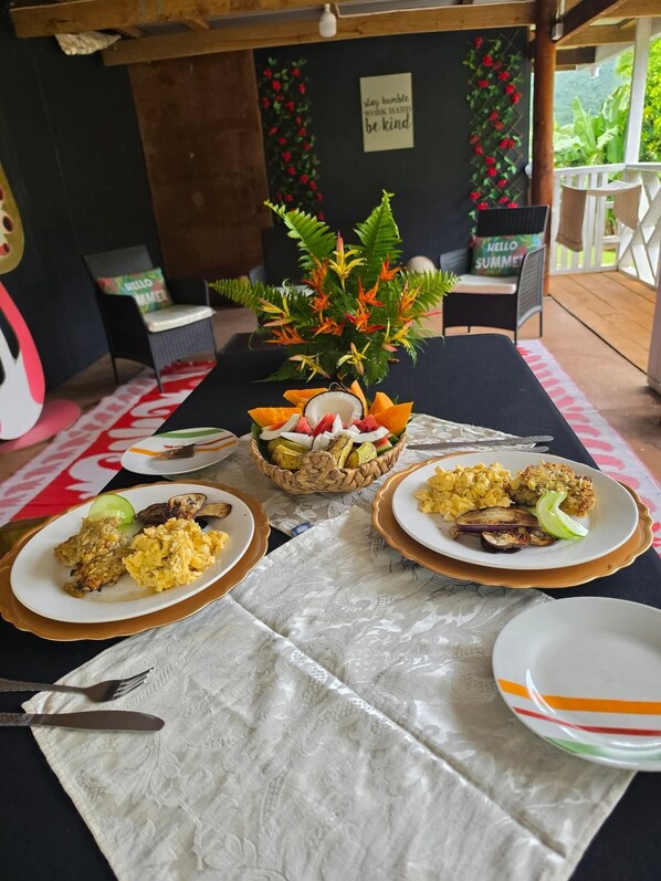 A dining table with plates of food, a decorative centerpiece, and a 'stay humble, work hard, be kind' sign in the background.