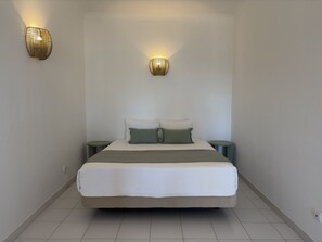 Ein Schlafzimmer mit einem Bett, zwei Nachttischen und zwei Wandleuchten.