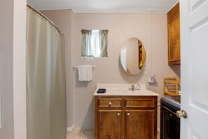 A bathroom with a wooden vanity, a mirror, a towel rack, and a shower curtain. - Comfy lake home near lakeside restaurants (Batesburg-Leesville)