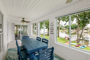 A covered patio with a table and chairs, large windows, and a view of a lake with boats. - Comfy lake home near lakeside restaurants (Batesburg-Leesville)