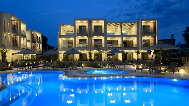 Un hotel moderno con piscina, lettini e ombrelloni.