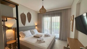 Camera d'albergo con un letto, una scrivania, una sedia, una televisione e un'ampia finestra con tende.
