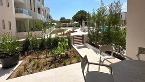 Un balcone con vista su una piscina, piante in vaso e una sedia.