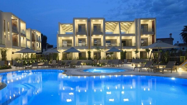 Un hotel moderno con piscina, lettini e ombrelloni.