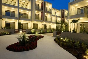 Ein mehrstöckiges Gebäude mit Balkonen, einem zentralen Innenhof mit Pflanzen und einem gut beleuchteten Eingang.