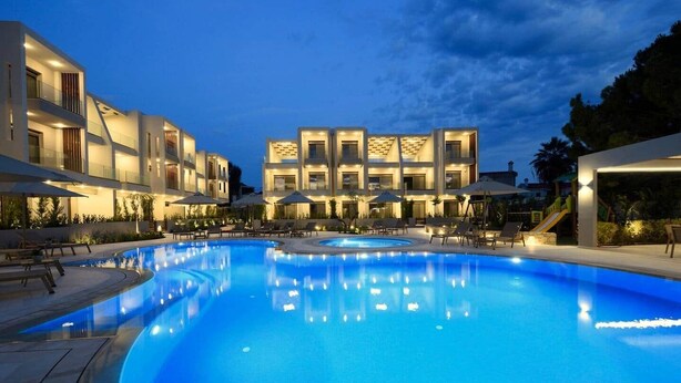 Una piscina con sillas de descanso, un área de juegos infantiles y edificios modernos con balcones.