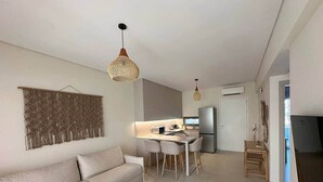 Una sala moderna con un sofá, una mesa de comedor con sillas y una cocina al fondo.