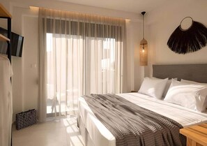 A hotel room with a large bed, a TV mounted on the wall, a ceiling light fixture, and a window with sheer curtains. - Villas Thallo № 3 (Neos Marmaras)