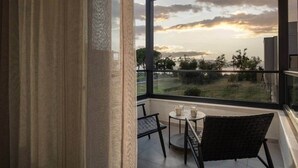 A balcony with a view of a sunset, a table with chairs, and a window with curtains. - Villas Thallo № 3 (Neos Marmaras)