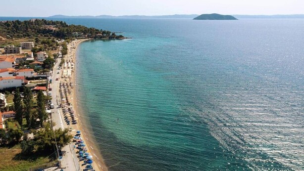 Eine Küstenansicht mit Strand, Gebäuden und einer entfernten Insel.