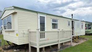 Une maison mobile dotée d’une terrasse à l’avant, d’une porte coulissante et d’une cheminée.