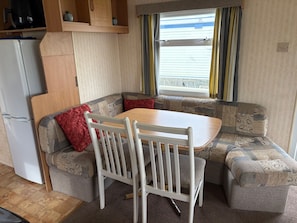 A compact kitchenette with a refrigerator, a wooden cabinet, and a coffee maker.