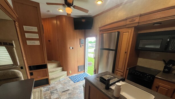 A compact kitchen with a refrigerator, microwave, stove, and sink. - Cardinal Camper Getaway at Eddy's Place-Sleeps 8 (Moravia)