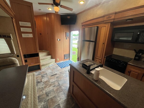 A compact kitchen with a refrigerator, microwave, stove, and sink.
