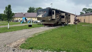 A recreational vehicle (RV) parked in a grassy area with a playground in the background. - Cardinal Camper Getaway at Eddy's Place-Sleeps 8 (Moravia)