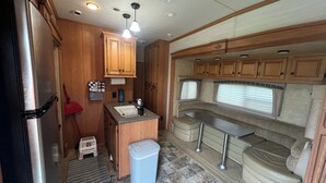 A compact RV kitchen with a refrigerator, sink, and wooden cabinets. - Cardinal Camper Getaway at Eddy's Place-Sleeps 8 (Moravia)