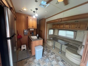 A compact RV kitchen with a refrigerator, sink, and wooden cabinets.