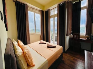 A hotel room with a bed, a desk, and a view of the outdoors. - Sun Dove Suit - Kandy (Kandy)
