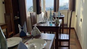 A dining area with a table set for two, a window with a view, and a wooden floor. - Sun Dove Suit - Kandy (Kandy)