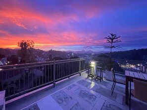 A terrace with a view of a sunset, a railing, and a table with chairs. - Sun Dove Suit - Kandy (Kandy)