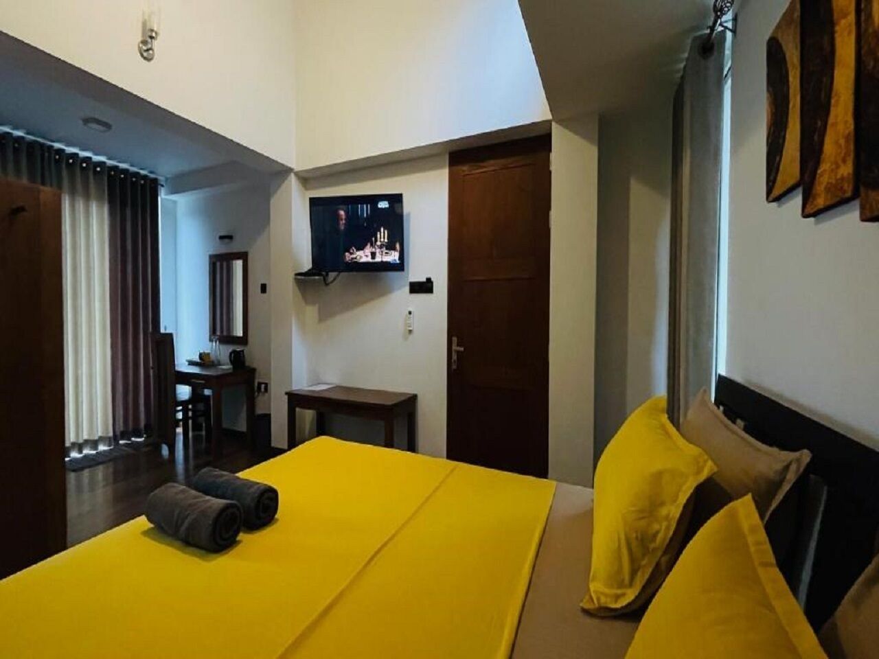 A hotel room with a bed, a TV, a desk, and a door.