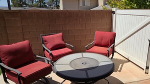 Eine Terrasse mit rundem Tisch und vier Stühlen, einer Ziegelwand und einem weißen Tor.