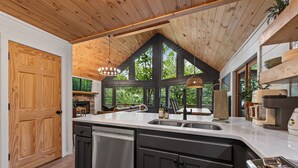 Een keuken met een groot eiland, houten plafond en grote ramen.