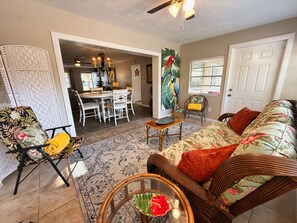 A living room with a dining area, a parrot painting, and a wicker chair. - Relaxed Clearwater Family Retreat with Private Pool and Patio (Clearwater)