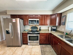 A kitchen with stainless steel appliances, wooden cabinets, granite countertops, and a built-in microwave. - Relaxed Clearwater Family Retreat with Private Pool and Patio (Clearwater)