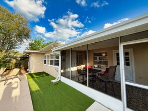 A covered patio with a table and chairs, a small lawn, and a view of the backyard. - Relaxed Clearwater Family Retreat with Private Pool and Patio (Clearwater)