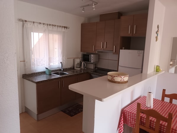 A compact kitchen with a sink, microwave, and a small dining area with a table and chairs.