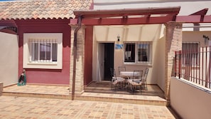Ein Haus mit gefliestem Patio, einer überdachten Sitzterrasse und einem verschlossenen Eingang.