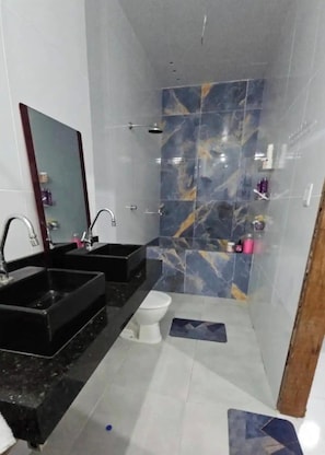 Een badkamer met twee wasbakken, een toilet en een douche.