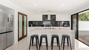 Een moderne keuken met een centraal eiland, roestvrijstalen apparatuur en een groot raam.