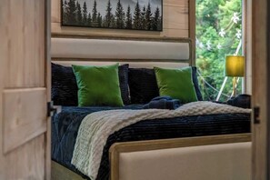 A bedroom with a bed, pillows, a blanket, a painting, and a lamp. - Gatlinburg 3BR | Indoor Pool + Pickleball Court (Gatlinburg)
