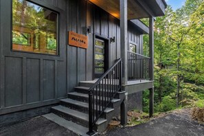 A wooden cabin with a sign reading 'Wyatt Crest Lodge' and a staircase leading to a porch. - 3-Bedroom Gatlinburg Cabin with Indoor Pool & Private Pickleball Court (Gatlinburg)
