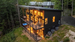 A multi-story cabin with a balcony, outdoor seating, and a visible pool. - 3-Bedroom Gatlinburg Cabin with Indoor Pool & Private Pickleball Court (Gatlinburg)