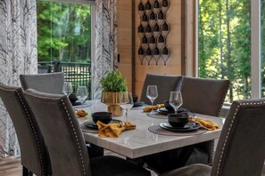 A dining table set for four with a view of greenery outside. - 3-Bedroom Gatlinburg Cabin with Indoor Pool & Private Pickleball Court (Gatlinburg)