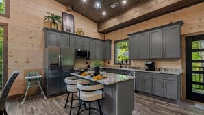 A modern kitchen with grey cabinets, stainless steel appliances, and a central island with bar stools. - Gatlinburg 3BR | Indoor Pool + Pickleball Court (Gatlinburg)