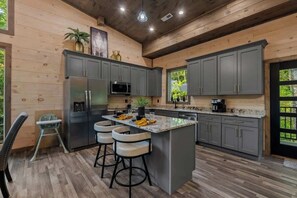A modern kitchen with grey cabinets, stainless steel appliances, and a central island with bar stools. - Gatlinburg 3BR | Indoor Pool + Pickleball Court (Gatlinburg)
