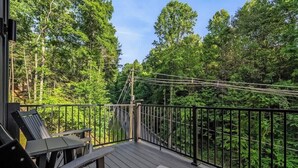 A wooden deck with a metal railing overlooking a forested area. - Gatlinburg 3BR | Indoor Pool + Pickleball Court (Gatlinburg)