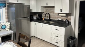 Una cucina moderna con mobili bianchi, un frigorifero in acciaio inossidabile, un piano di lavoro nero e un lavello.