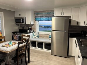 Uma cozinha compacta com micro-ondas, fogão, geladeira e uma janela com vista.