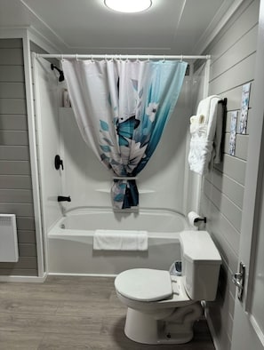 Um banheiro com banheira, vaso sanitário e cortina de chuveiro.
