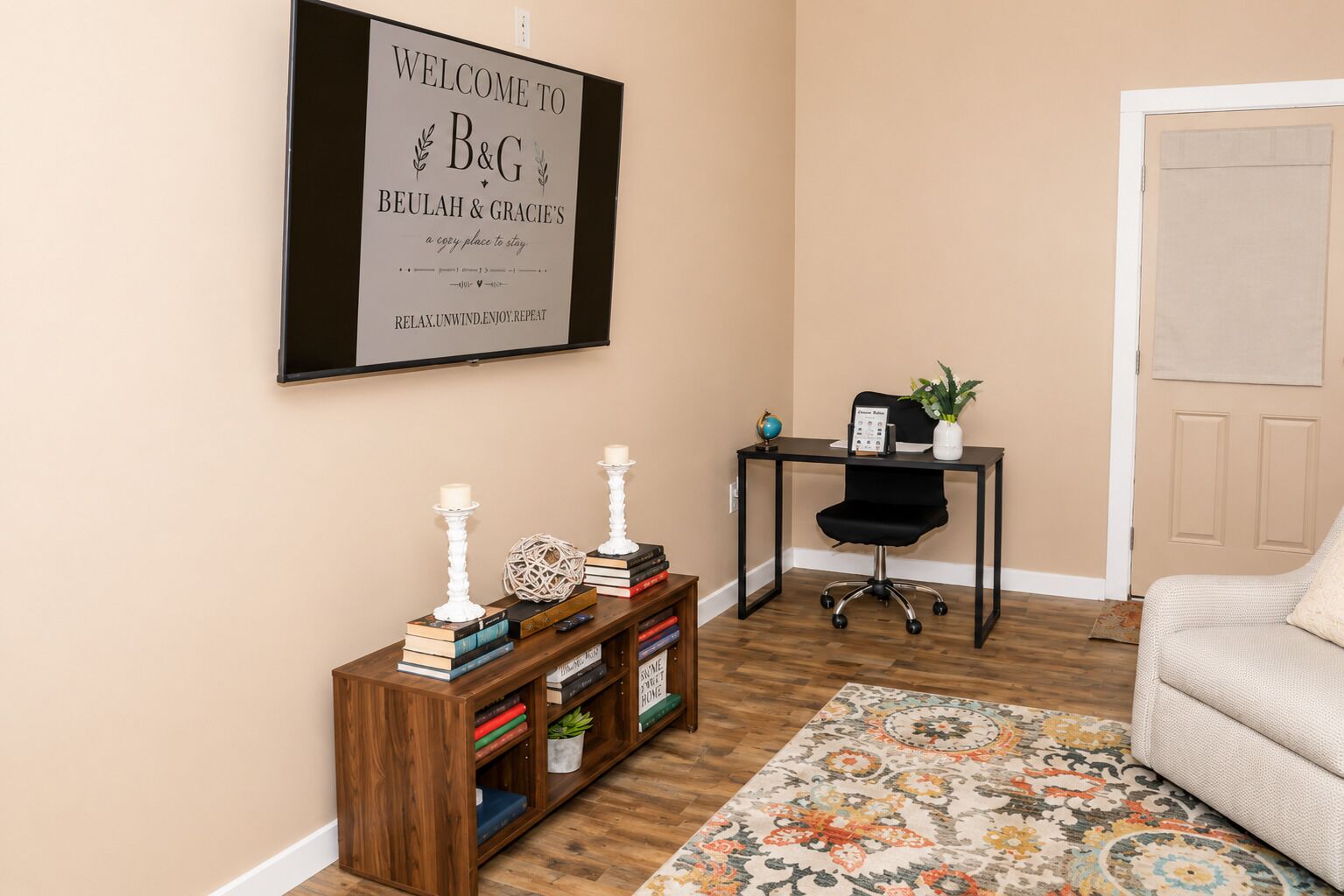 Een kamer met een bureau, stoel, boekenplank en een welkomstbord.