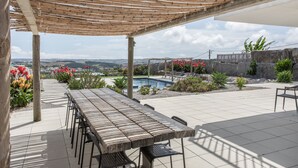 Un patio cubierto con piscina, mobiliario exterior y vistas al paisaje.