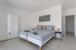 A bedroom with two beds, a wardrobe, a painting, and a bedside table with a lamp. - Room 'Sapphire' with Shared Pool, Shared Terrace and Wi-Fi (Lourinhã)