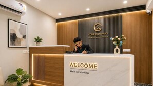 Una recepción con un cartel de 'WELCOME', un logotipo encima y un hombre sentado detrás del mostrador.