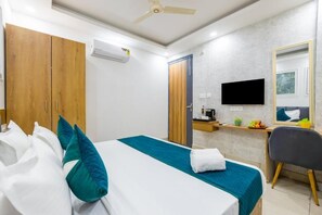Una camera d'albergo con un letto, una scrivania, una sedia, una televisione e un armadio.