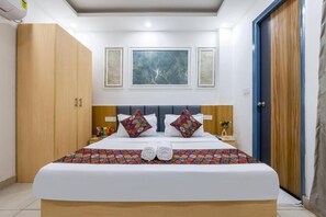 Una camera d'albergo con un letto, un armadio, un comodino e una porta.